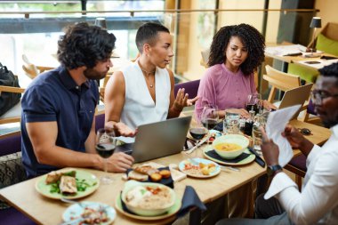 Business partners sit in a restaurant during business lunch and talk about a start-up business.