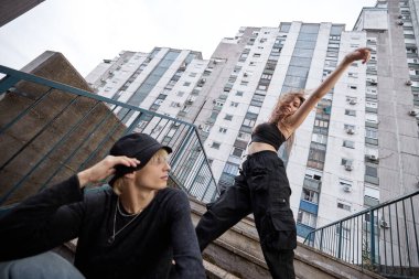 Teenagers are posing on the stairs in the urban exterior.