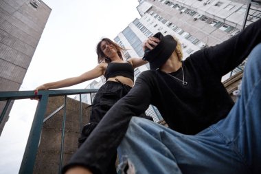 Teenagers are posing on the stairs in the urban exterior.