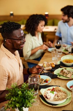 A multicultural man is having dinner with friends in a restaurant.