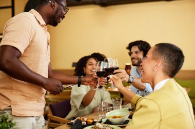 A Group of friends is toasting in a restaurant during dinner.