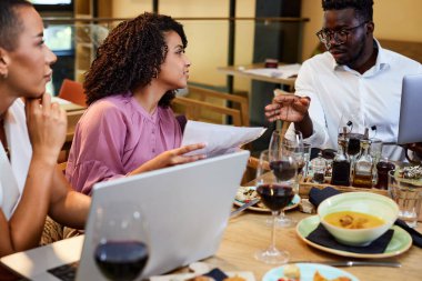 Afrikalı bir iş adamının bir restorandaki yemek masasında iş arkadaşlarına sunumu var..