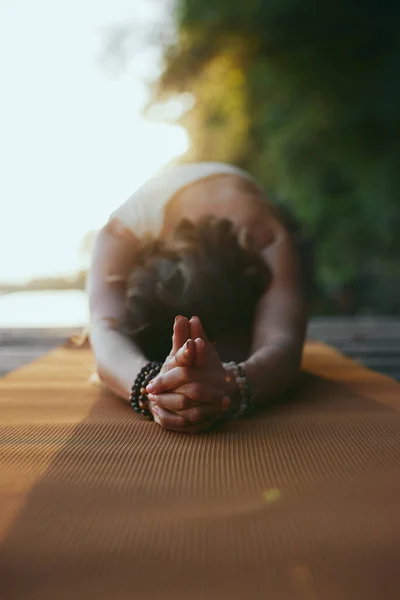 A woman practices yoga on the dock.