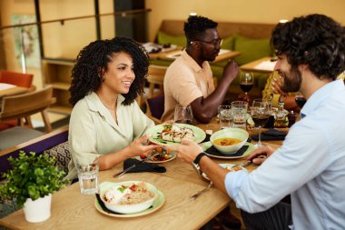 A multicultural woman is having dinner with friends in a restaurant.