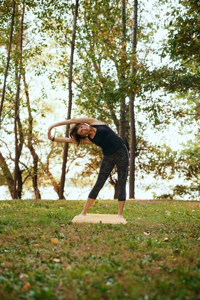 A yogi woman practices yoga in the forest in autumn.