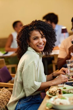 A smiling Hispanic girl is having dinner in a restaurant.