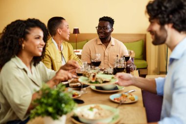 A multicultural friends are having dinner in a restaurant.
