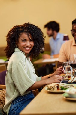 A smiling Hispanic girl is having dinner in a restaurant.
