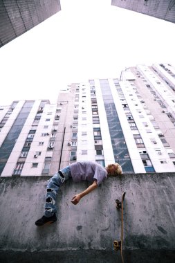A teenage boy is lying on the fence outside and feeling misunderstood.
