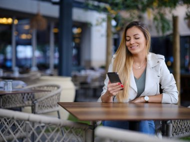 Mutlu bir kadın bir kafede oturur ve cep telefonu uygulamasından içki ısmarlar..