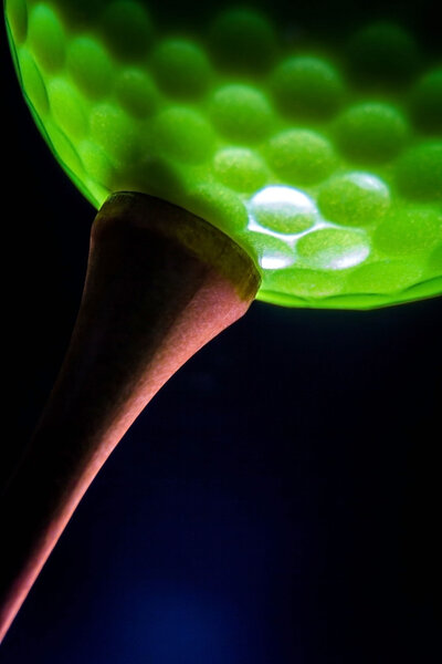 Green golf ball on the wood tee