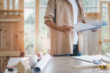 Miğfer takan yaşlı mimar, yapıyı teftiş etmek için mavi iz taşıyor, marangozluk atölyesinde çalışan usta marangoz, DIY hobisinin tadını çıkarıyor.. 