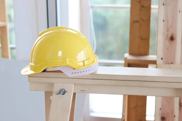 木工工場での木製テーブルの上に黄色の抗ノックヘルメット 職場のコンセプトでの個人用保護具 Ppe — ストック写真