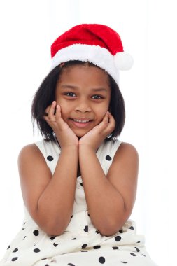 Noel 'i kutlamak için kırmızı Noel Baba şapkası takan sevimli Asyalı Afrikalı kızın portresi. Mutlu, tatlı, küçük bir çocuğun elleri üzerinde dinlenmesi.