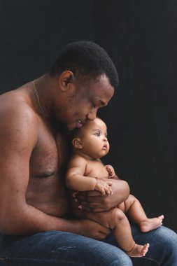 Babasının siyah arka planında kucağında küçük bir Asyalı Afrikalı yeni doğmuş bebek babasının kollarında sevimli bir bebeğin portresi, kucağında bir ebeveynin bebeği..