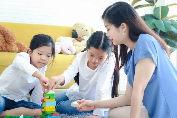 两个女儿在客厅和妈妈玩木块游戏 Jenga 孩子姐姐和妈妈在一起度过了一段特殊的时光 — 图库照片
