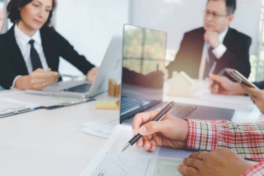 Hand of business man holding a pan while sitting at meeting table in office together with his colleague team, taking a short note and writing on paper during brainstorming meeting