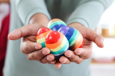 Ellerinde gökkuşağı Paskalya yumurtaları, LGBT elleri LGBQ geyleri ve lezbiyenlerin bayrak renklerine boyanmış renkli yumurtalar..