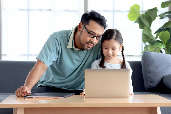 年轻英俊的爸爸教可爱的女儿做作业 在家里用笔记本电脑进行电子学习 爸爸和孩子在一起学习和上网 — 图库照片