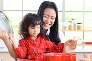 Mutlu gülümseyen genç anne ve küçük sevimli kızı sürpriz kırmızı hediye kutusunu açıyorlar, anne çocukla özel zaman geçirmekten hoşlanıyor. Sevgi ve sıcaklık aile kavramı.