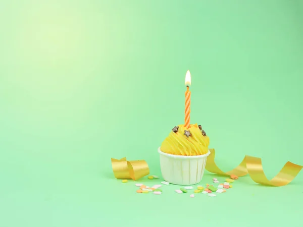 コピースペースと緑の背景に弓キャンドルと甘い黄色のカップケーキ ハッピーバースデーパーティーの背景コンセプト — ストック写真