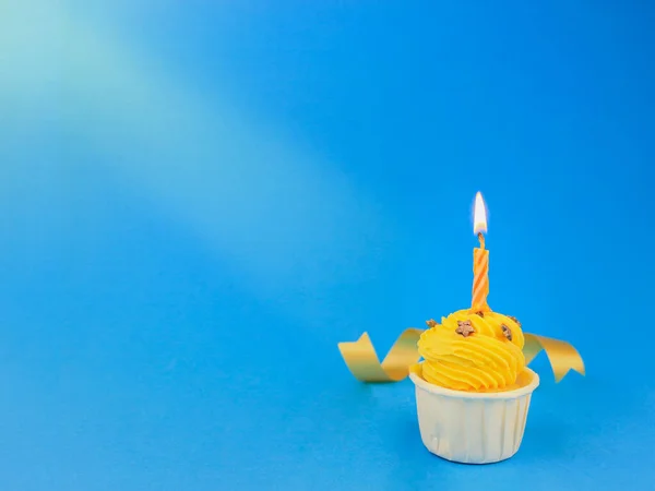 甜而明亮的黄色纸杯蛋糕 蓝色背景上有弓形蜡烛 还有复制空间 生日快乐派对 — 图库照片