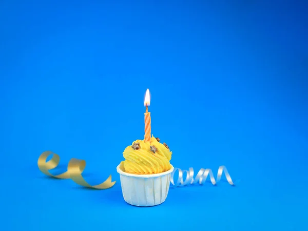 甜而明亮的黄色纸杯蛋糕 蓝色背景上有弓形蜡烛 还有复制空间 生日快乐派对 — 图库照片