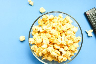 Lezzetli karamelli patlamış mısır mavi arka planda tatlı tatlı, favori film zamanları için cam kasede atıştırmalıklar.. 
