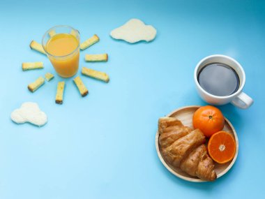 Yaratıcı kahvaltı fikri, bulutlu sabah mavi gökyüzü, portakal suyu, çıtır ekmek yağı şekeri, bulutlu beyaz ekmek, kruvasan, sıcak siyah kahve ve portakal meyvesi. C vitiniyle aydınlık bir günde uyanmak..