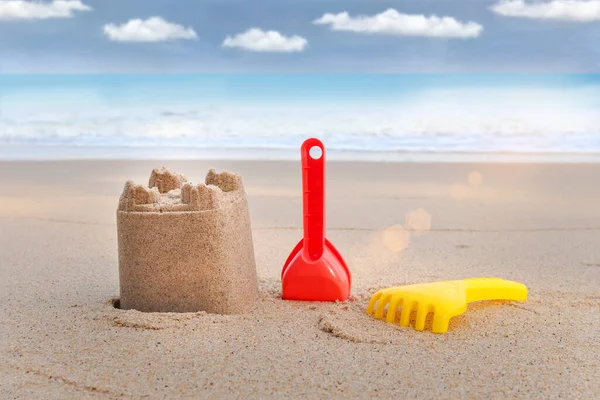 Sand castle and sand toys for making sandcastle on tropical sandy summer ocean beach with beautiful blue sky as background, relaxing outdoor vacation on sea beach island.