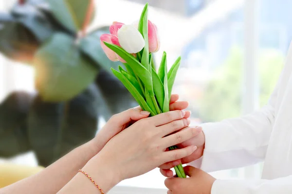 Beautiful tulip bouquet on hand, daughter giving flowers for her mother and mom taking them, warm love in family, Happy mother day, kid have special time with mom