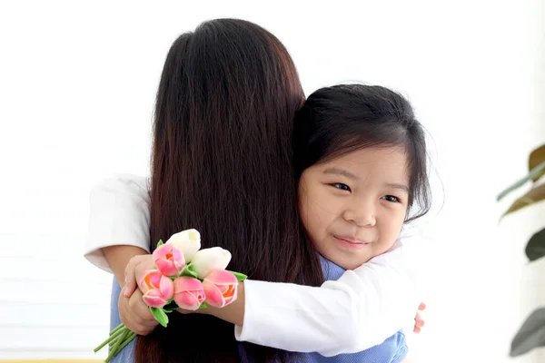 Adorable Asia happy smiling daughter girl giving beautiful tulip flowers for her mother and hugging her mom with love, warm love in family, Happy mother day, kid have special time with mom