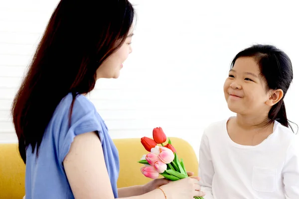 Adorable Asia happy smiling daughter girl giving beautiful tulip flowers for her mother with love, warm love in family, Happy mother day, kid have special time with mom.