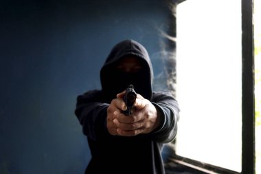 Siyah kapüşonlu bir suçlu, elinde silah tutan bir kurban, elinde silahı olan bir hırsız terk edilmiş bir binada suç işlemek için.