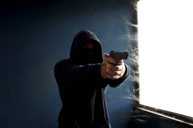 Siyah kapüşonlu bir suçlu, elinde silah tutan bir kurban, elinde silahı olan bir hırsız terk edilmiş bir binada suç işlemek için.