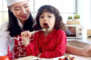 Çikolata kaplı, gülümseyen tatlı küçük kız ve yüzü çikolata kaplı, sevimli kız çocuğu güzel, genç annesiyle vakit geçirmenin tadını çıkarıyor. Aile sıcaklığını seven anne ve çocuk kavramını.