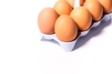 Beyaz bir plastik hücredeki tavuk yumurtaları beyaz arka planda köşegen olarak yer alıyor.