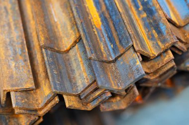 Endüstriyel bir depoda bir sürü paslı çelik köşe var. Metalden yapılmış çeşitli mühendislik yapıları için malzeme. Yakın plan.