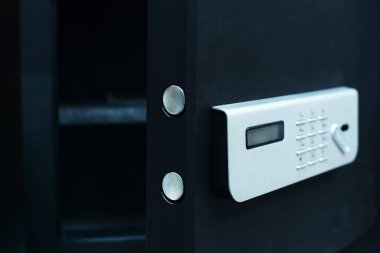 Metal safe with a combination lock. A fragment of an open storage of a small size with an electronic panel. Black color. Close-up