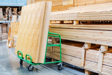 Large sheets of plywood lie on a transport cart in a building supplies store. Copy space
