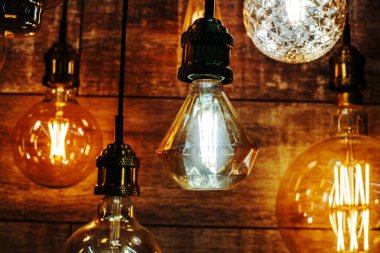 LED bulbs of different sizes and shapes against a wooden wall. Retro style lighting equipment trade. Close-up