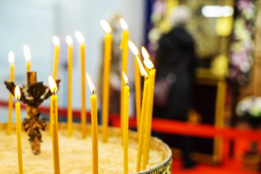 Church candles in the temple against the background of icons and parishioners. Selective focus. Foreground