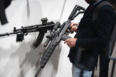 A man tests firearms in a specialty store. Samples of machine guns on the showcase of the trading network. Close-up. Unrecognizable person