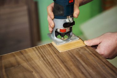 Bir kaplama ürününün kenarlarını değirmenleme işlemi. Elektrikli modemle mobilya yapıyorum. Yakın plan.