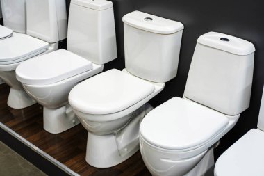 Bir dükkan camında farklı tipte seramik klozetler. Özel bir mağazada hijyenik ekipman satışı. Yakın plan.