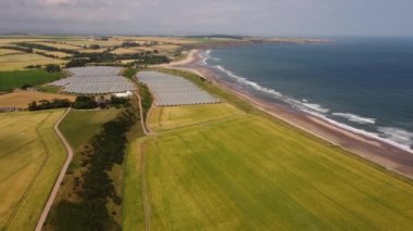 Kuzey denizinin kıyı şeridi yeşil tarlaların ve seraların yanında yer alır. Dron görünümü.