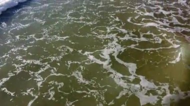 Üzerinde beyaz köpük ve güzel lekeler olan okyanus dalgaları üzerinde uçan dron..