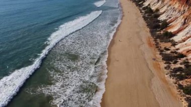 Drone view of small ocean surf on a sandy beach in Southern Portugal.