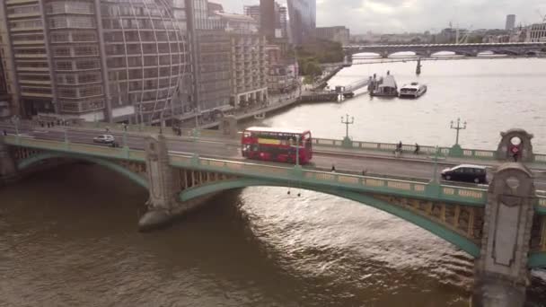 Zdjęcie lotnicze Southwark Bridge z czerwonym dwupokładowym autobusem jadącym nad nim. — Wideo stockowe
