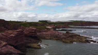 Arka planda seralar olan kayalık bir sahil manzarası.